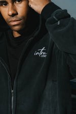 Person wearing a TOXIC LOVE zip up jacket with 'intra one' branding against a dark background