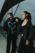 Two people wearing toxic love zip up jackets with unique designs, standing outdoors.