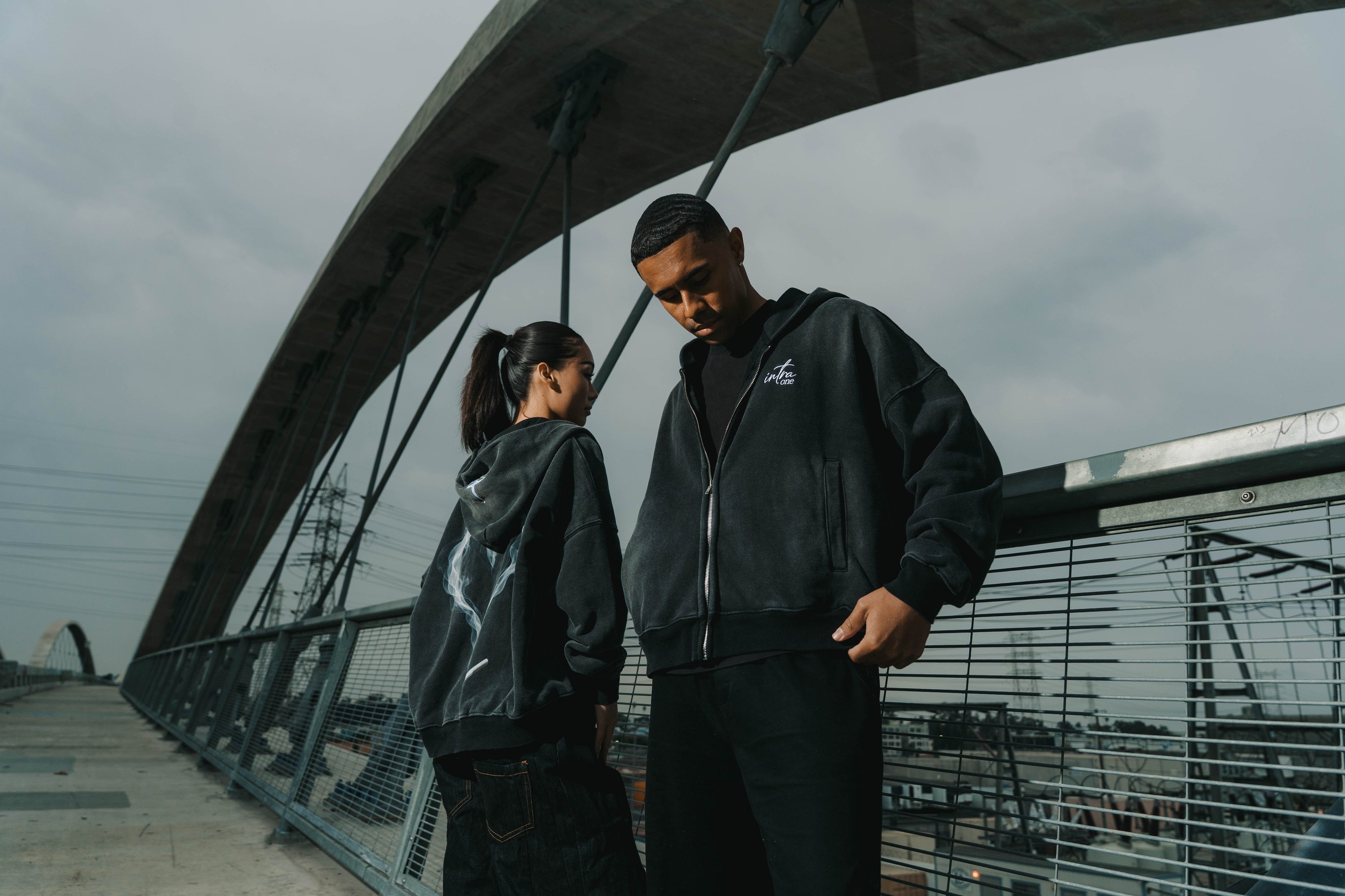 Two models standing on LA's sixth street bridge wearing INTRA ONE's toxic love zip up jackets