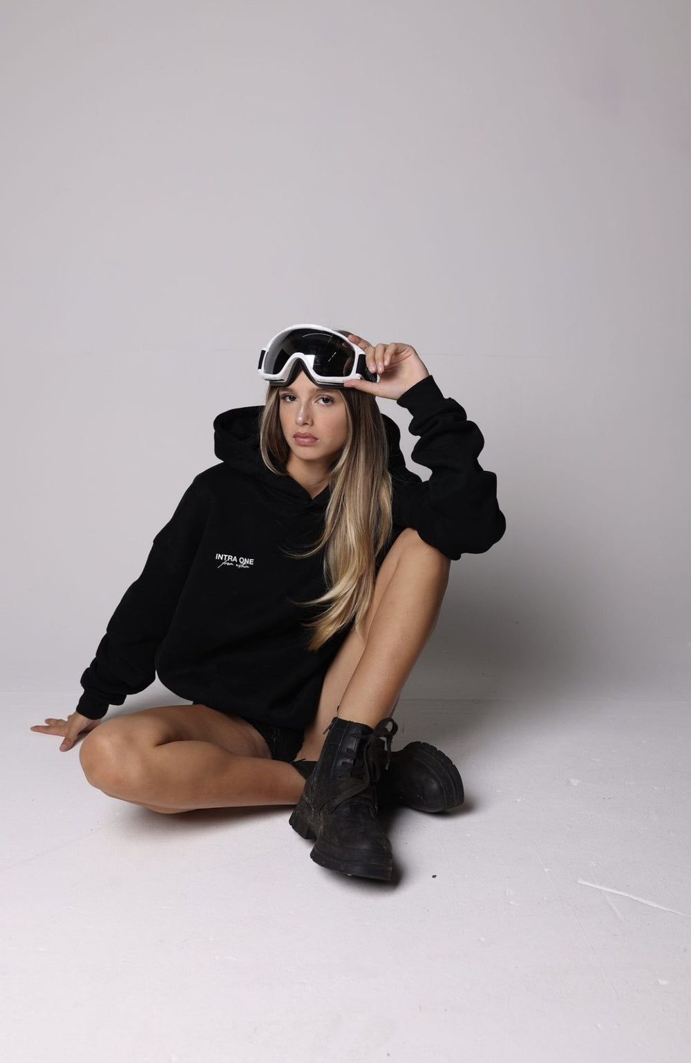 _christina_bliss_ sitting wearing INTRA ONE's signature hoodie in black