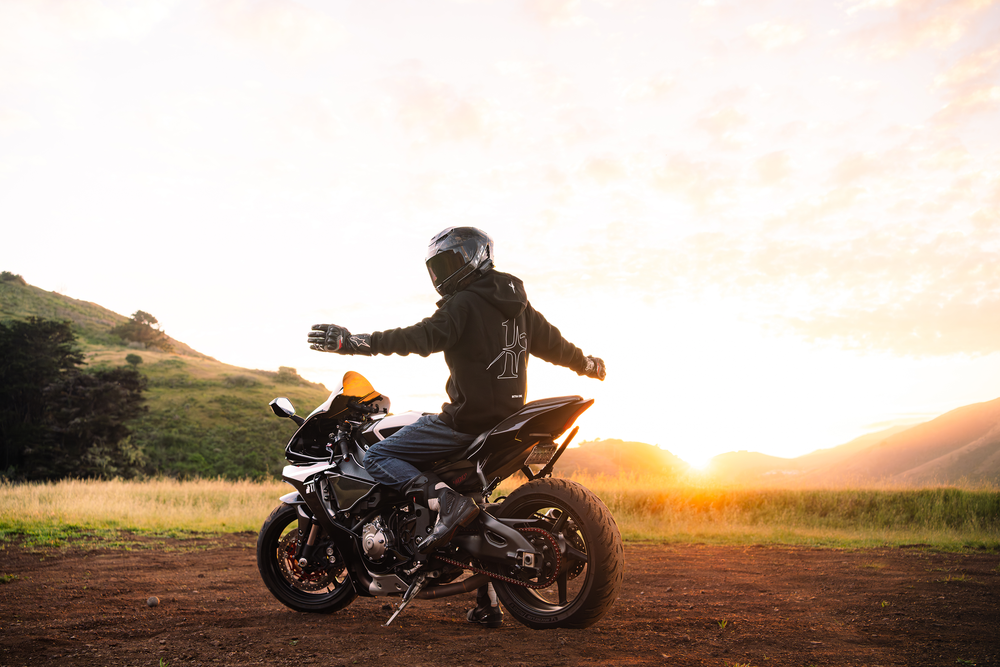 specterr1 wearing INTRA ONE's black signature hoodie on his motorcycle in the sunset