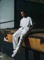 Male model wearing INTRA ONE signature sweats in white, sitting at night in a dark setting for a streetwear fashion shoot